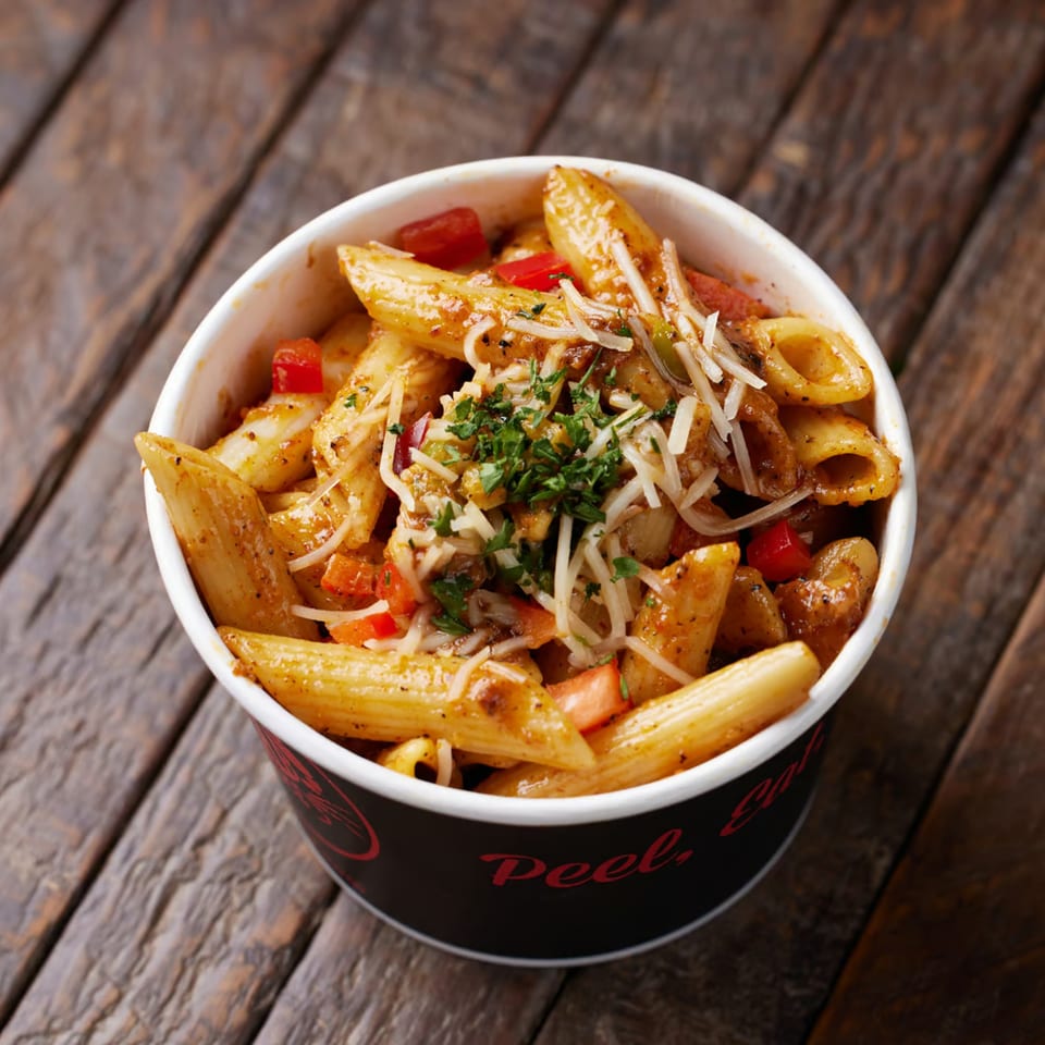 Penne pasta with red sauce, bell peppers, and shredded cheese in a Crab N Spice cup.