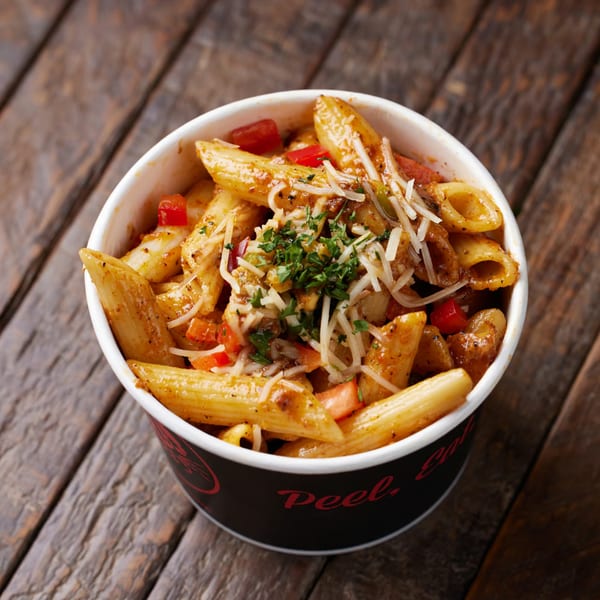 Penne pasta with red sauce, cheese, and parsley in a black and white Crab N Spice cup.